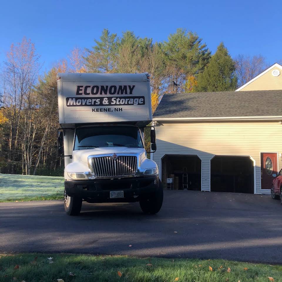 Economy Movers truck sitting in the driveway in front of a tan colored garage