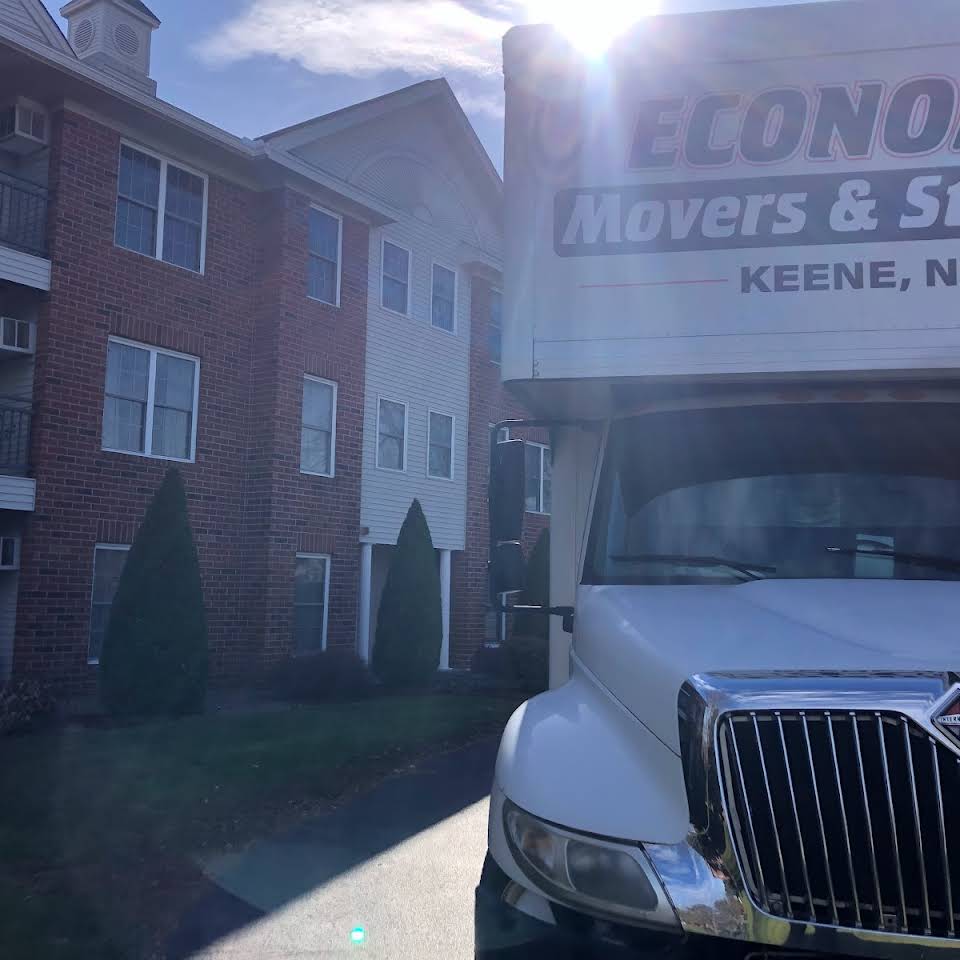 Economy Movers truck outside of a red brick apartment building