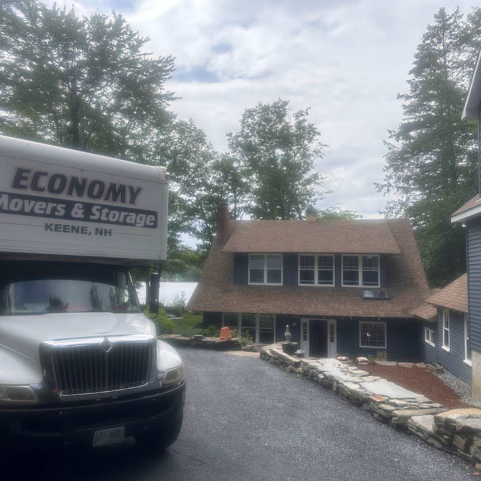 Economy Movers truck sitting in driveway of a two level brown house